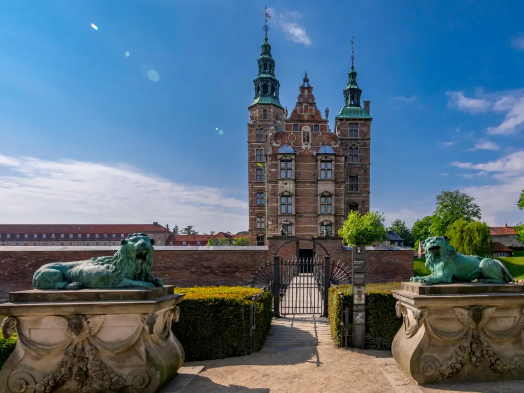 Rosenborg Castle in Copenhagen Denmark with bronze lion statues guarding the entrance on a sunny day
