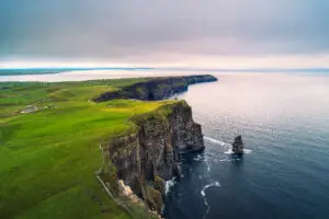 Aerial view of the scenic Cliffs of Moher in Ireland with dramatic sea cliffs, lush green landscape, and Atlantic Ocean coastline, a popular tourist destination on the Wild Atlantic Way.