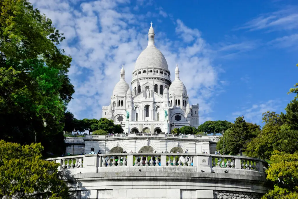 Sacre-Coeur Basilica in Montmartre Paris France with blue sky and greenery, popular tourist attraction and landmark for European private tours