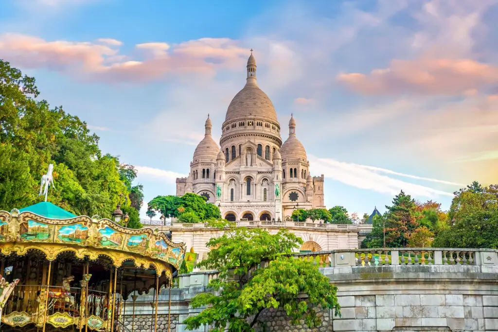 Sacre Coeur Basilica in Montmartre Paris France with colorful carousel and sunset sky, popular tourist attraction on European private tours