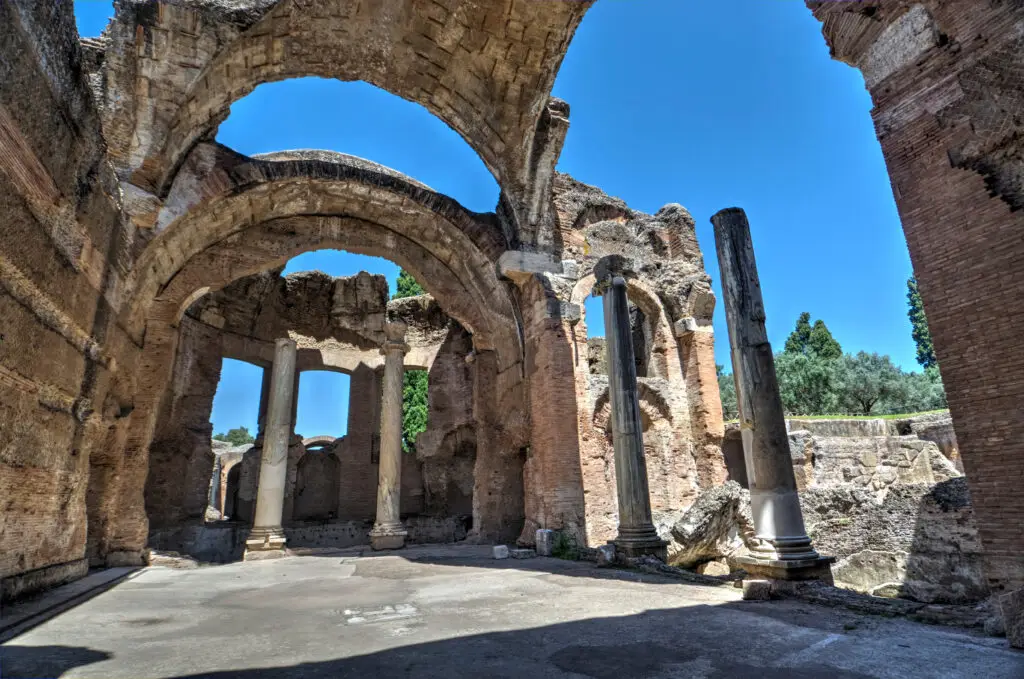 Ancient Roman ruins at Villa Adriana in Tivoli Italy with stone arches and marble columns under a bright blue sky