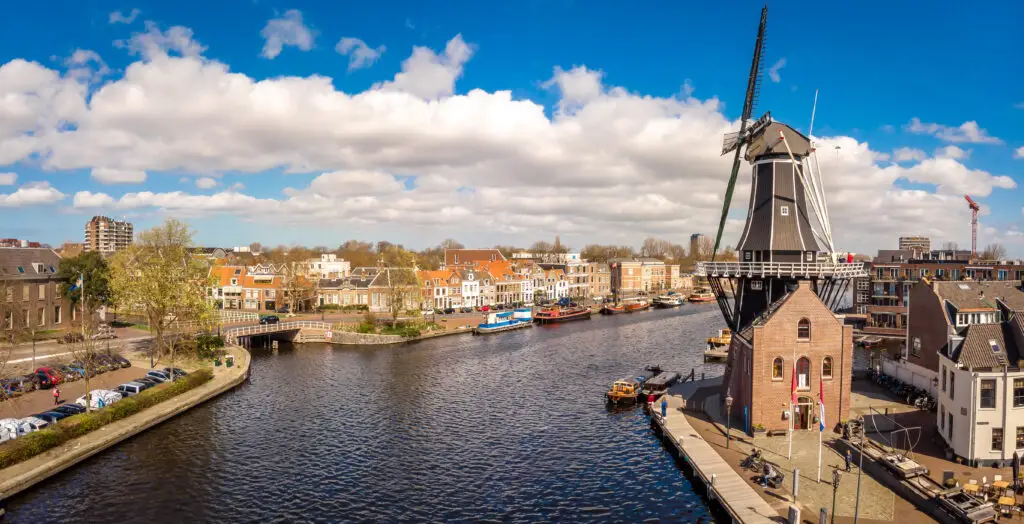 Aerial view of traditional Dutch windmill and canal in Haarlem, Netherlands, featuring historic houses and boats, popular tourist attraction in the Netherlands