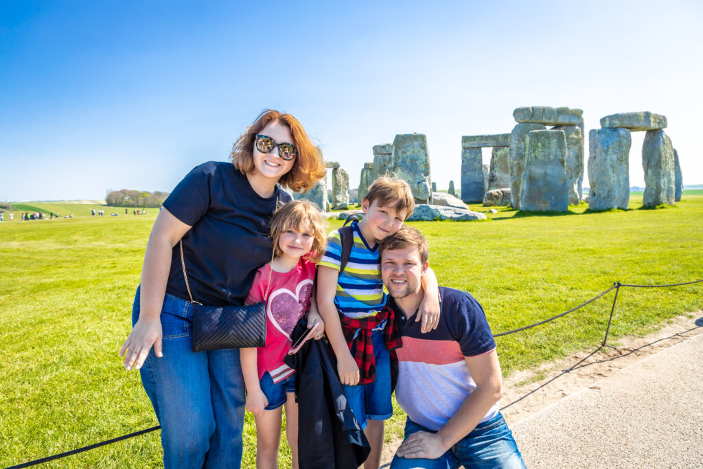 Happy family visiting Stonehenge in summer, England on a bright sunny day during a private Europe tour