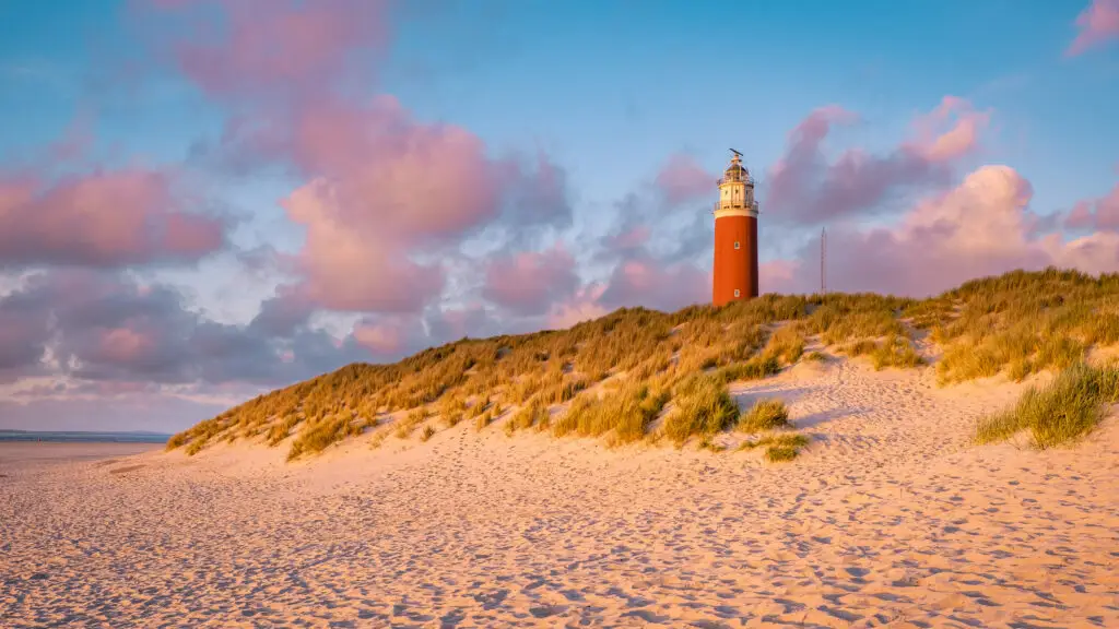 Red lighthouse on sandy dunes at sunset on Texel Island, Netherlands, popular Dutch tourism attraction in Holland