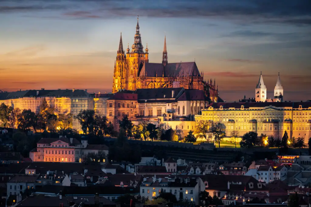 Prague Castle and St. Vitus Cathedral illuminated at sunset overlooking the city skyline in Prague, Czech Republic