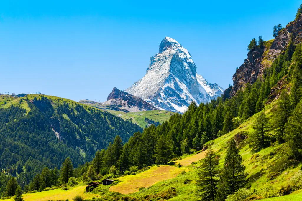 Snow-capped Matterhorn mountain in the Swiss Alps with green meadows and pine forests in Zermatt, Switzerland, popular European travel and hiking destination
