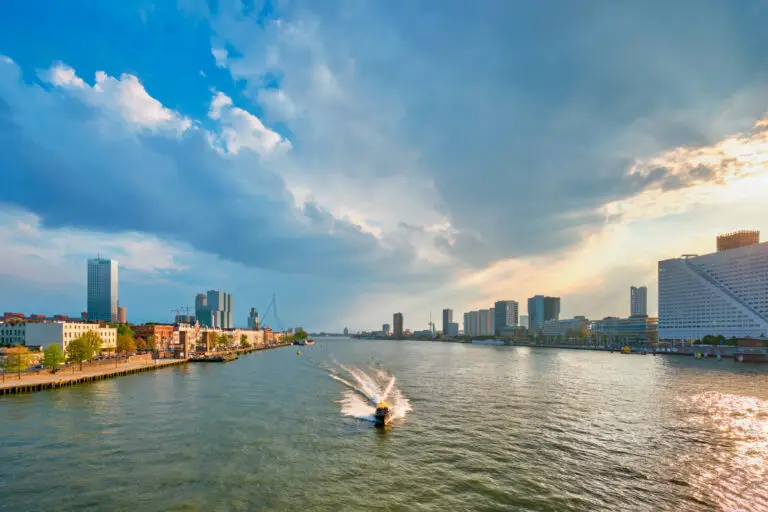 Rotterdam cityscape with Erasmus Bridge and boat on the Nieuwe Maas River at sunset, Netherlands