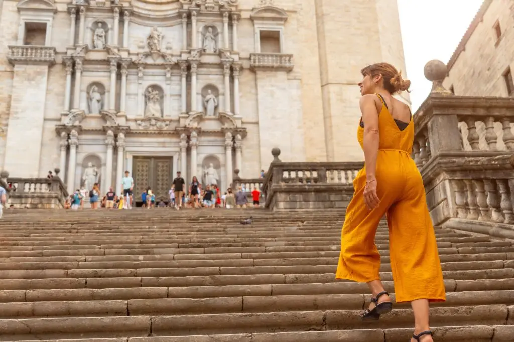 Tourist walking up the stone steps toward the Cathedral of Girona in Spain, a popular historic landmark and travel destination in Catalonia