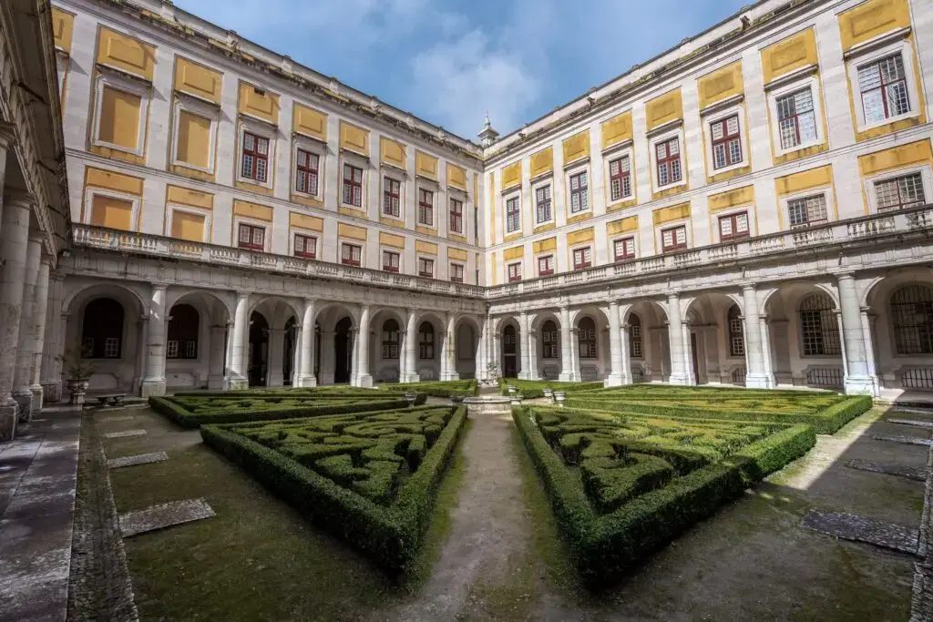 Courtyard garden of the Mafra National Palace in Mafra, Portugal, featuring manicured hedges and classical architecture popular with European cultural tours