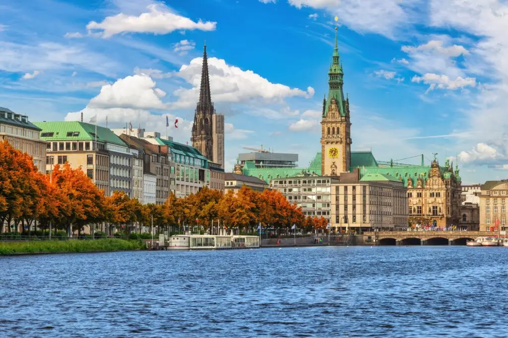 Scenic view of Hamburg Germany with the historic Town Hall and churches along the Alster River under a bright blue sky