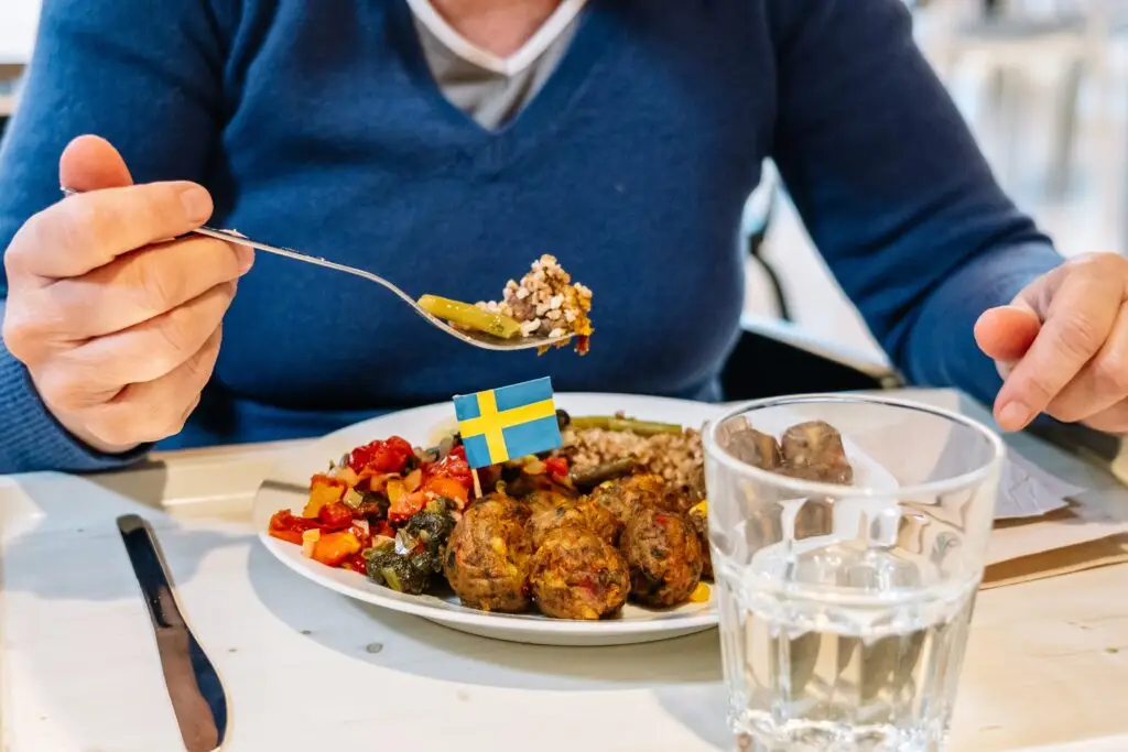 Traditional Swedish meal with meatballs, vegetables, and a small Swedish flag in a restaurant in Stockholm, Sweden