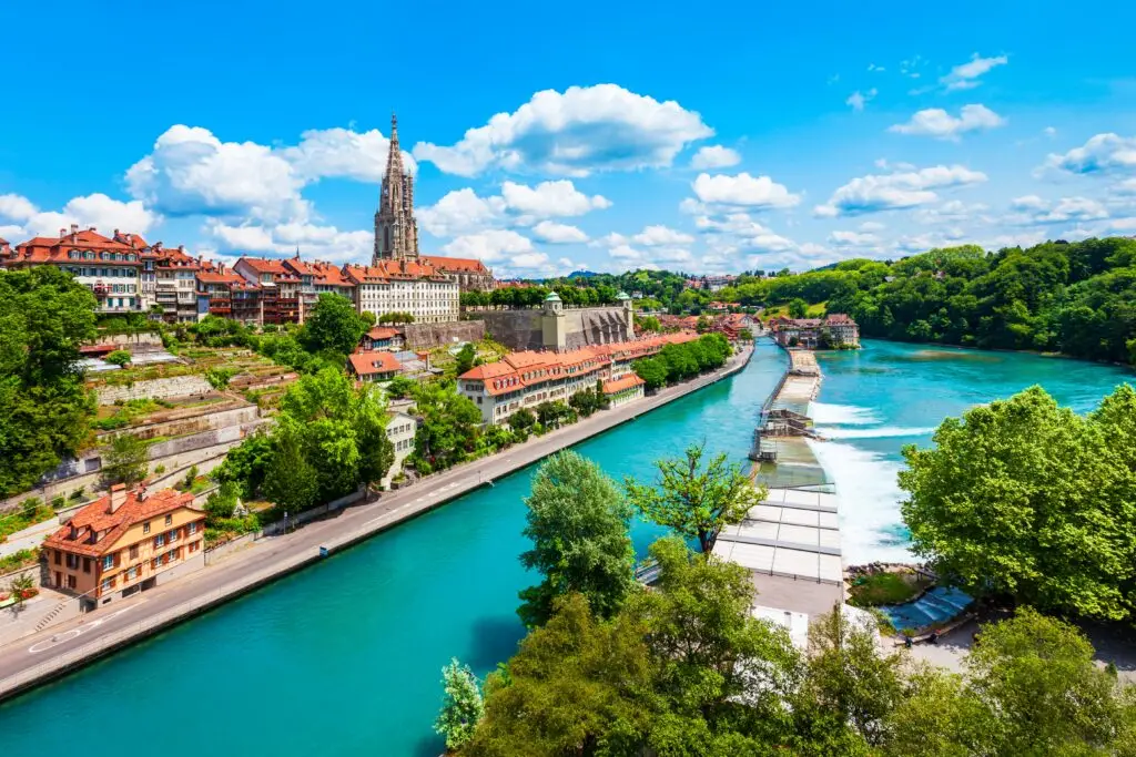 Scenic view of Bern Switzerland with the Aare River, old town architecture, and Bern Cathedral on a sunny day