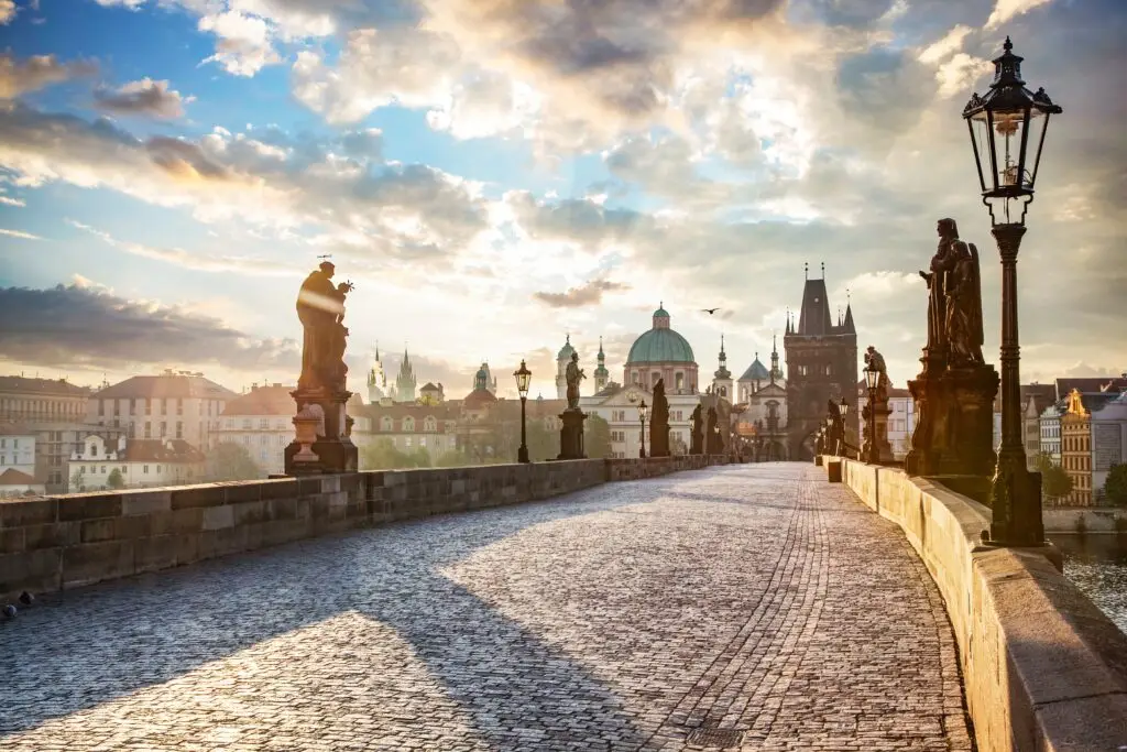 Charles Bridge in Prague Czech Republic with historic statues and city skyline at sunrise