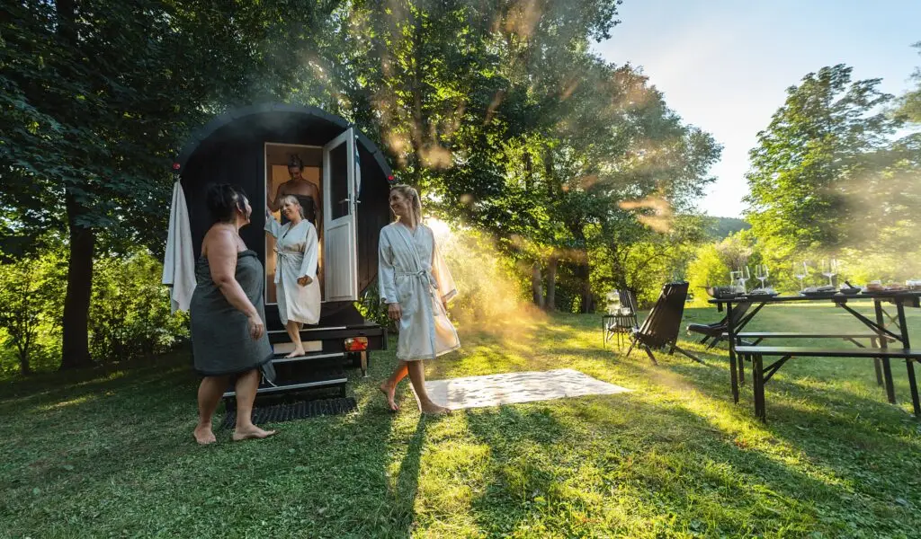 Friends enjoying a relaxing outdoor wooden barrel sauna experience in nature during a European private tour