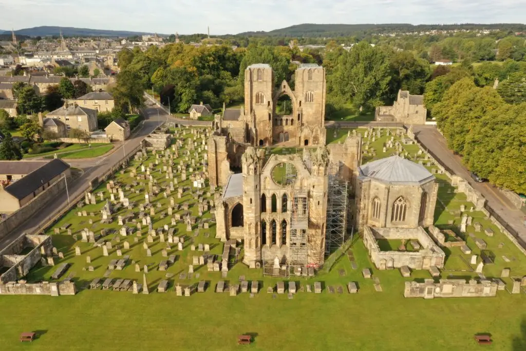 Aerial view of Elgin Cathedral ruins in Moray, Scotland, surrounded by historic graveyard and scenic countryside, a popular tourist attraction on European private tours.