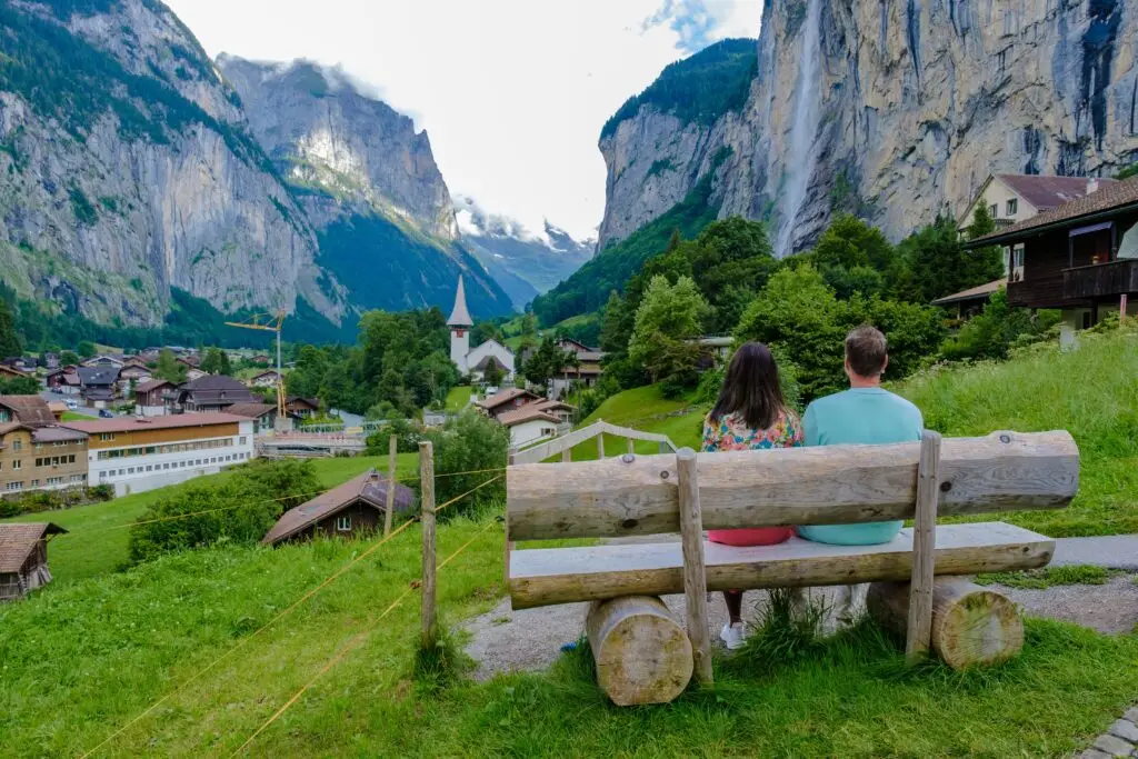 Couple enjoying scenic view of Lauterbrunnen Valley with Staubbach Falls and Swiss Alps in Switzerland