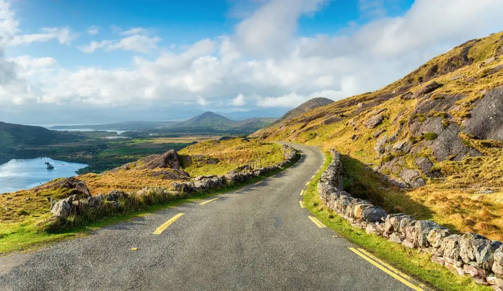 Scenic view looking north along the Healy Pass with Glanmore Lake and surrounding mountains in County Kerry, Ireland, showcasing a winding road and vibrant green landscape ideal for European private tours
