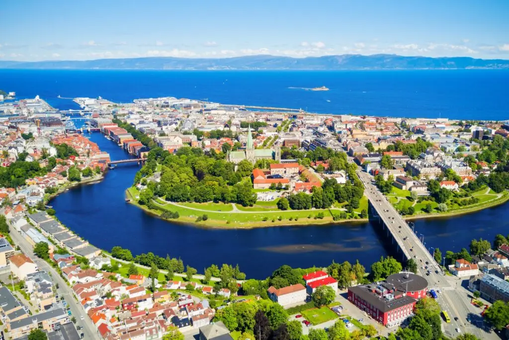 Aerial view of Trondheim, Norway showcasing the Nidaros Cathedral, colorful buildings, and scenic waterfront along the Nidelva River on a sunny day