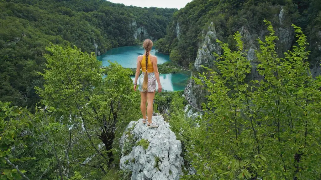 Woman admiring the turquoise lakes and lush green landscape at Plitvice Lakes National Park in Croatia