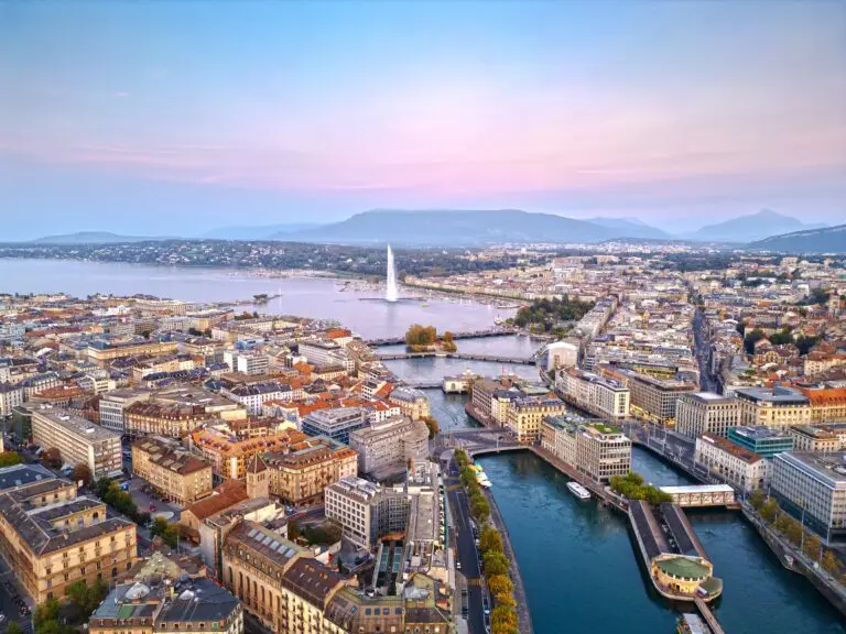 Aerial view of Geneva Switzerland featuring the Jet d’Eau fountain, Lake Geneva, and city architecture at sunset