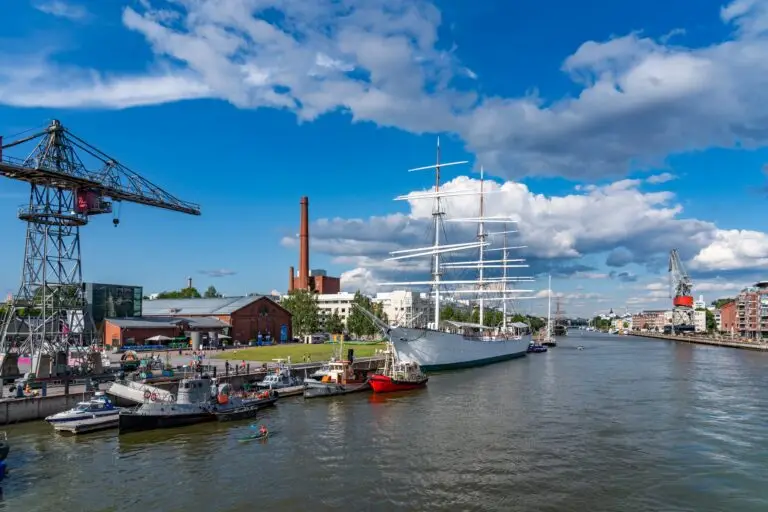 Sailing ship and boats docked at Turku Harbour with waterfront views, historic buildings, and industrial cranes in Turku, Finland