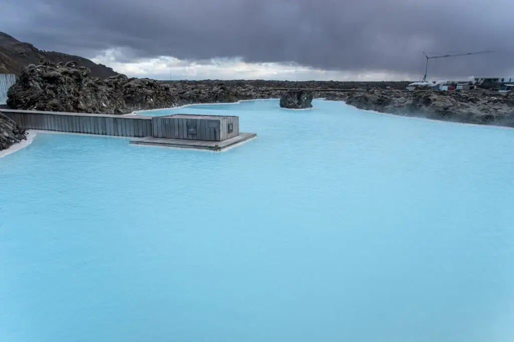 Geothermal lagoon with bright blue water surrounded by volcanic rocks at the Blue Lagoon in Iceland, a popular spa and tourist attraction.
