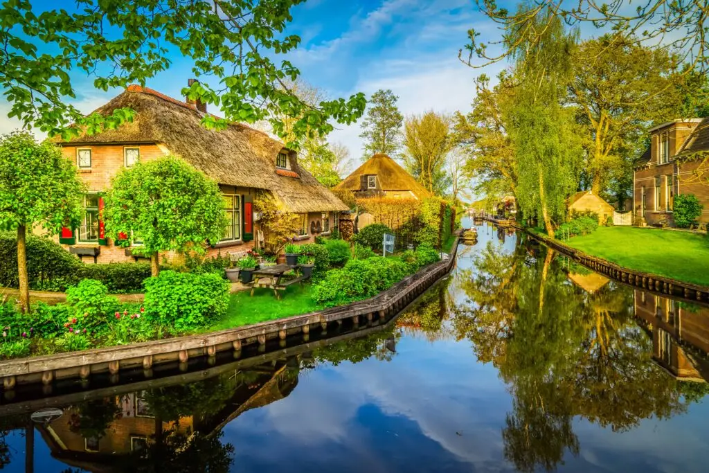 Picturesque canal view in Giethoorn, a traditional Dutch village with thatched-roof houses, lush gardens, and calm waterways in the Netherlands countryside
