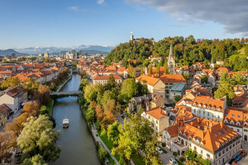 Aerial view of Ljubljana, Slovenia with the Ljubljanica River, red-roofed buildings, and Ljubljana Castle on the hill in the background