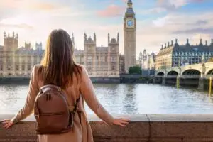 Tourist admiring Big Ben and the Houses of Parliament along the River Thames in London England during a private sightseeing tour