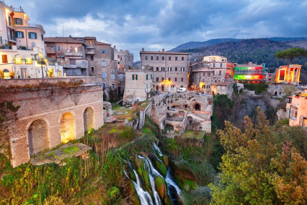 Historic architecture and waterfalls in Tivoli, Italy, featuring ancient Roman ruins and scenic hillside views at sunset