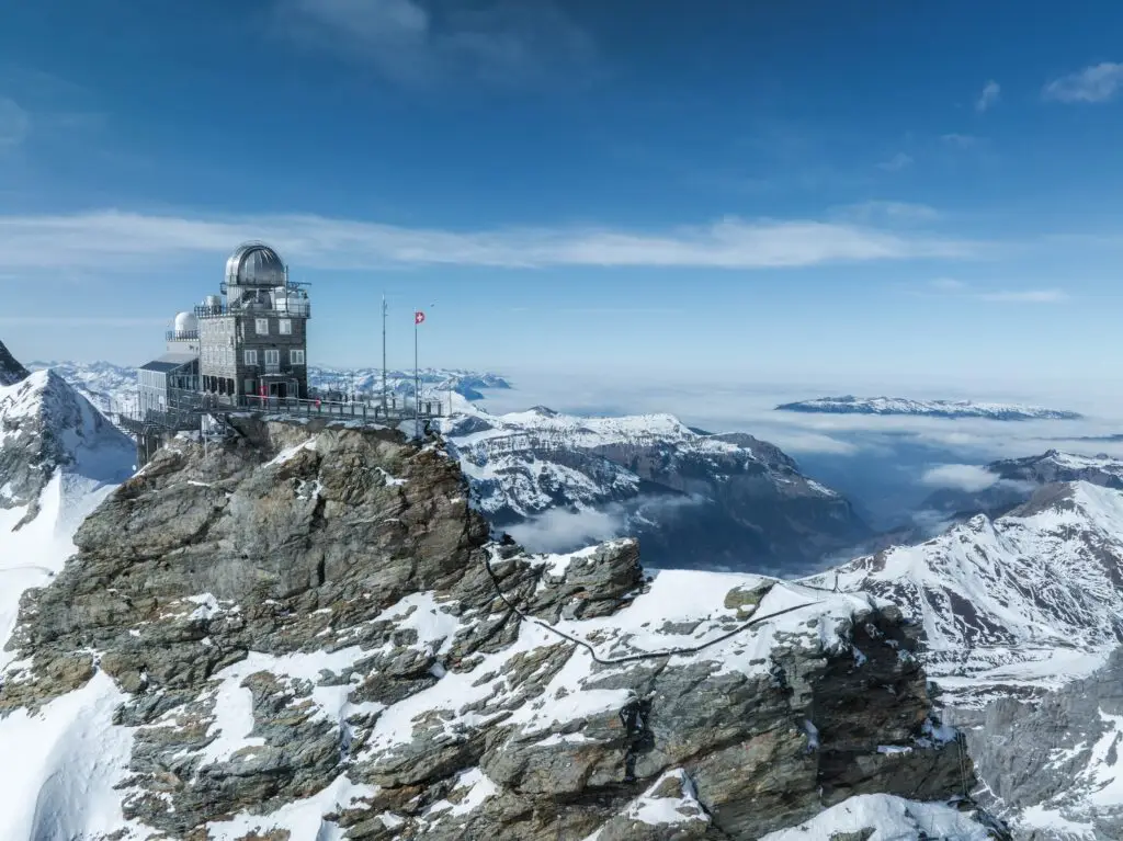 Jungfraujoch Observatory overlooking snow-covered Swiss Alps mountains in Switzerland, a popular Europe private tour destination for scenic travel and sightseeing.