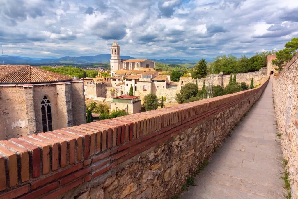 Historic city walls and old town view of Girona, Spain with the Cathedral of Girona and scenic mountain backdrop