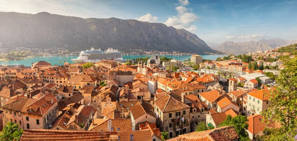 Panoramic view of Kotor, Montenegro with red-roofed old town, cruise ship in the Bay of Kotor, and scenic mountains in the background