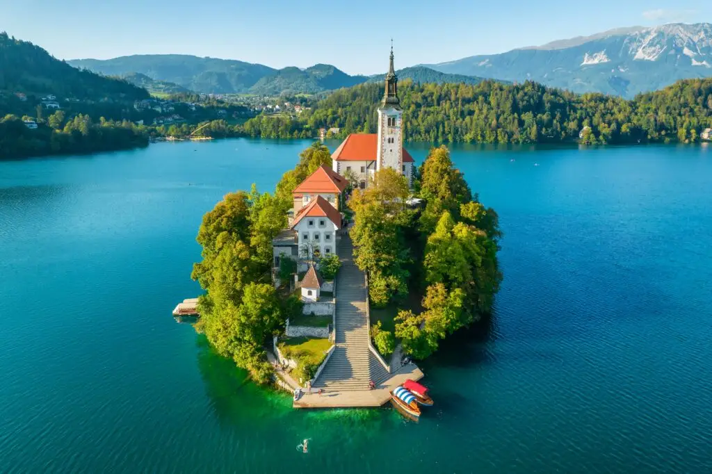 Aerial view of Lake Bled island with the Church of the Assumption surrounded by turquoise water and mountains in Slovenia