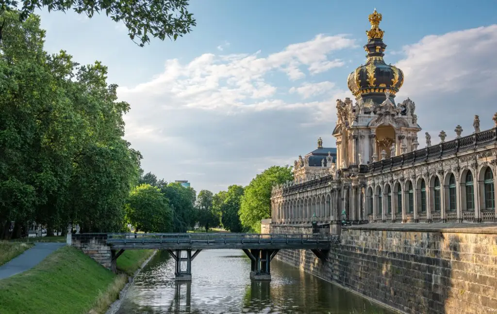 Evening view of the historical Zwinger Palace in Dresden, Germany with ornate baroque architecture and scenic water reflection, popular European tourist attraction