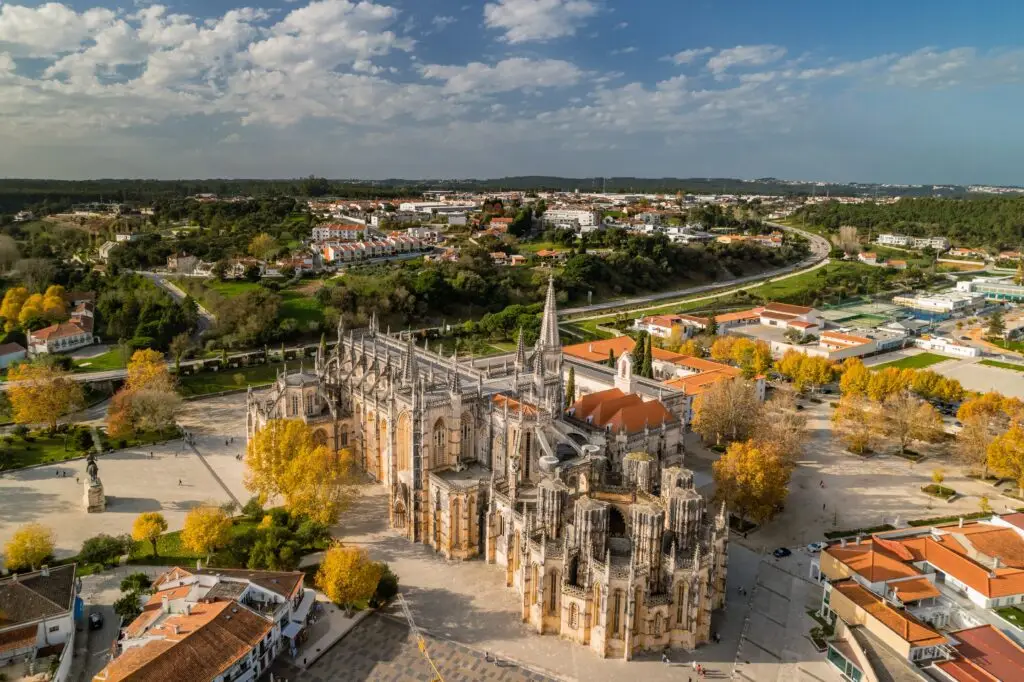 Aerial view of the Monastery of Batalha in Batalha, Portugal, a UNESCO World Heritage Site and popular tourist destination surrounded by scenic town architecture and autumn trees