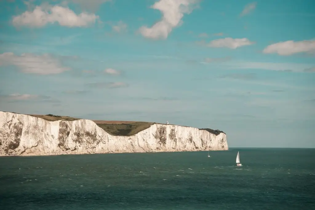 White Cliffs of Dover overlooking the English Channel in the United Kingdom with sailboats on the sea, popular British Isles tourist attraction