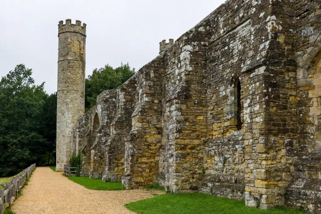 Ruins of the medieval abbey with stone walls and tower surrounded by greenery in England Europe historic site tour attraction