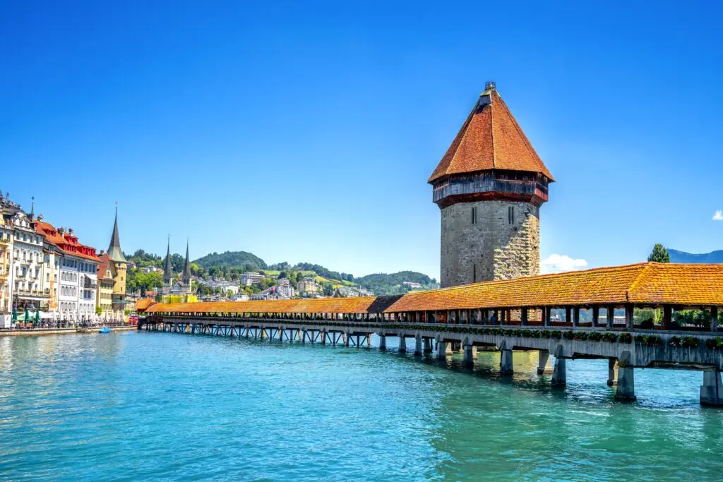 Chapel Bridge and Water Tower over the Reuss River in Lucerne Switzerland on a sunny day with historic buildings and alpine scenery