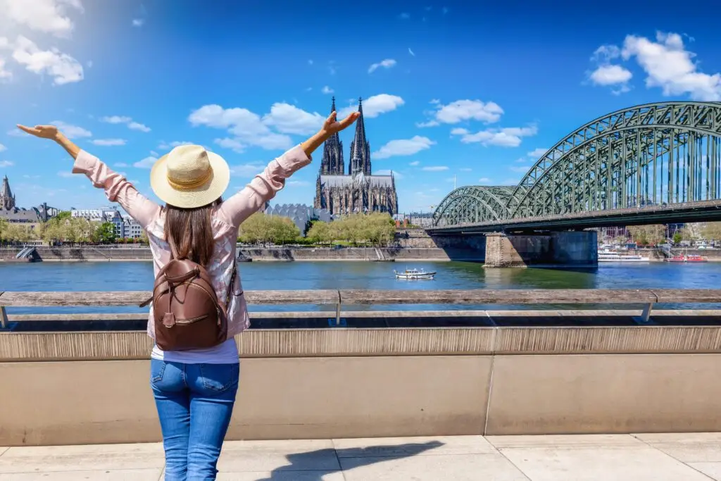 Tourist enjoying the view of Cologne Cathedral and Hohenzollern Bridge over the Rhine River in Cologne, Germany