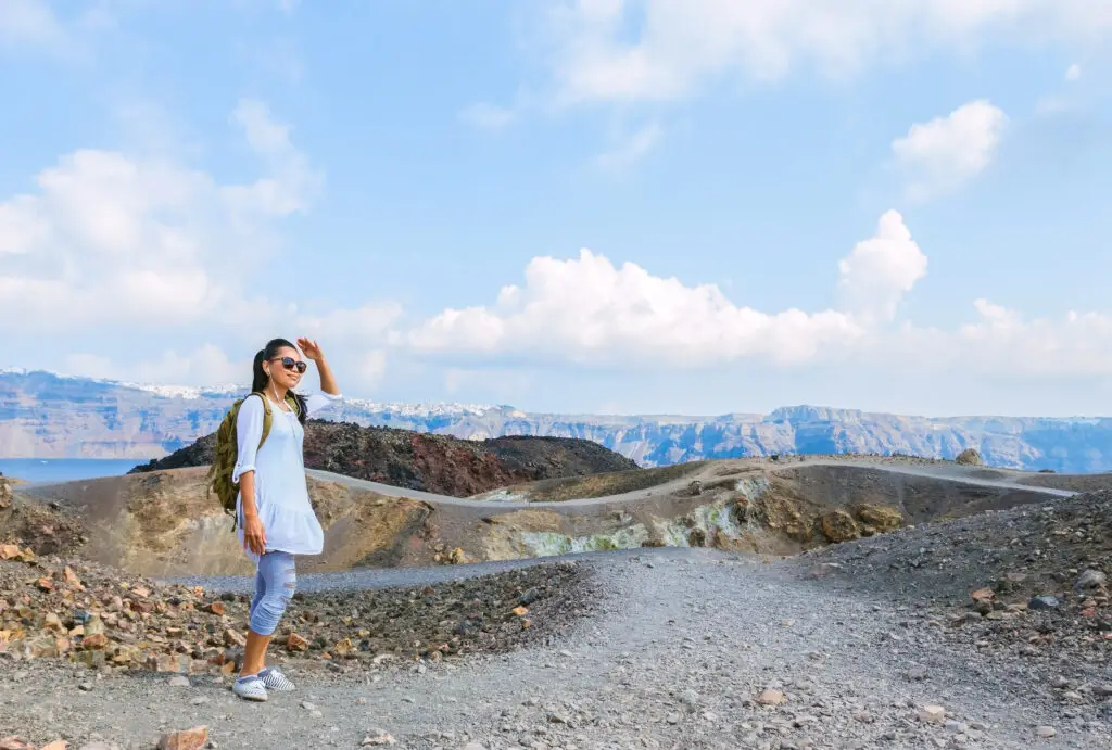 Female tourist enjoying panoramic view on Nea Kameni volcanic island in Santorini Greece during a private European tour