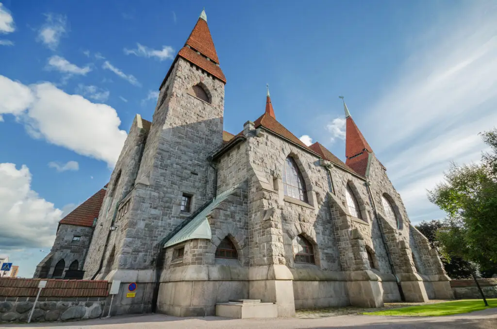 Tampere Cathedral in Finland with distinctive stone architecture and red spires under a blue sky, popular tourist attraction in Tampere