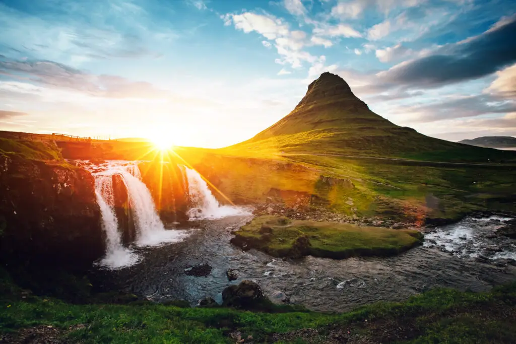 Scenic view of Kirkjufell mountain and waterfall at sunset in Iceland, popular tourist destination for photography and nature tours