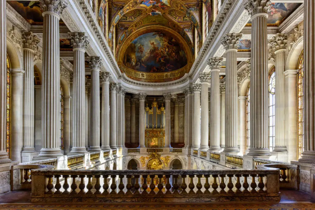 Interior view of the Royal Chapel in the Palace of Versailles in France showcasing grand columns, ornate gold details, and a beautifully painted ceiling