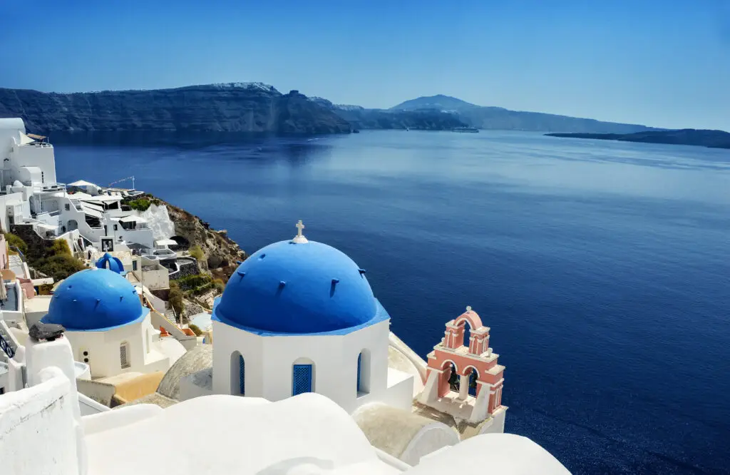 Scenic view of the caldera from Oia village in Santorini Island, Greece, featuring whitewashed buildings with blue domes overlooking the Aegean Sea