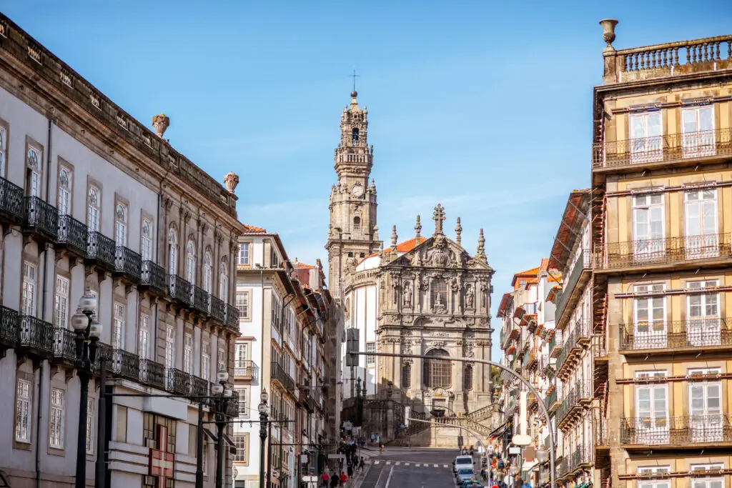 Historic city street view with the Clerigos Church and Tower in Porto, Portugal, showcasing baroque architecture and traditional European buildings on a sunny day