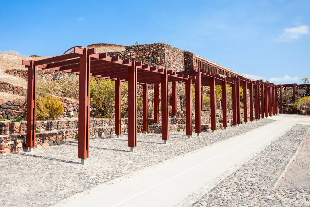 Akrotiri Archaeological Site Museum near Fira on Santorini Island in Greece with ancient stone walls and wooden walkway under clear blue sky