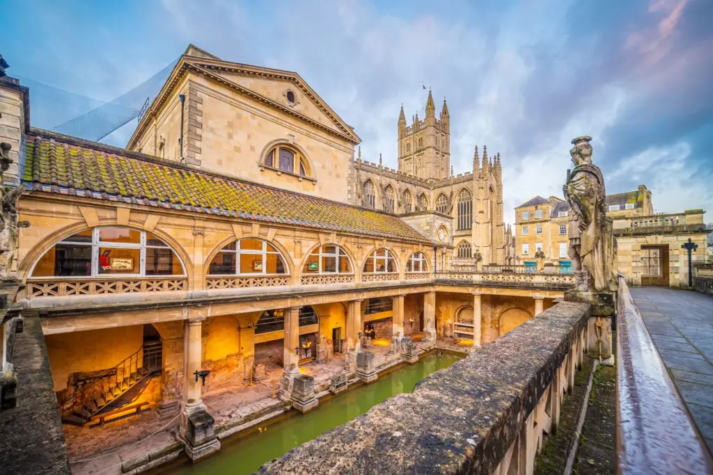 Historic Roman Baths in Bath City, England at twilight with ancient architecture and cathedral in the background, popular tourist attraction for Europe private tours